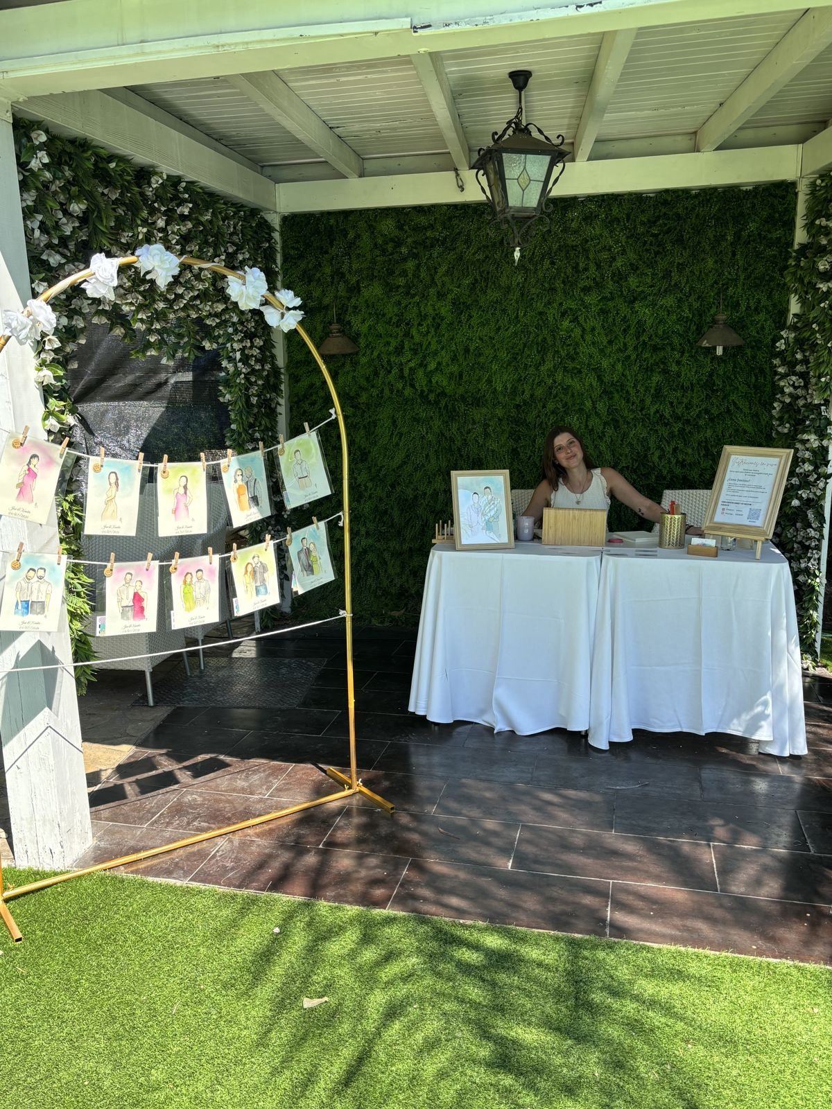 Stand de acuarela en vivo con arco expositor y mesa vestida de blanco