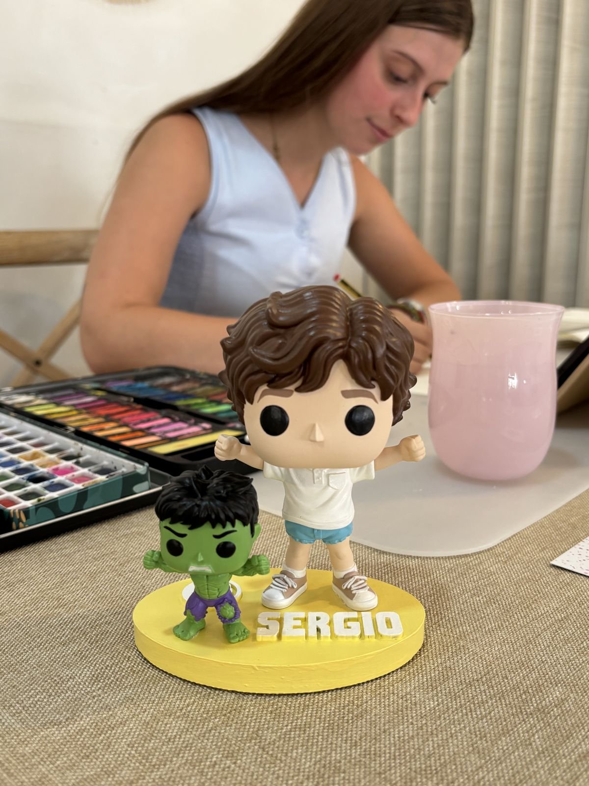 Naiara pintando un Funko personalizado junto a su paleta de acuarelas